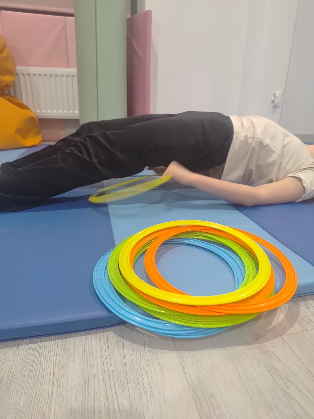 Dziecko wykonuje ćwiczenie ruchowe na materacu podczas terapii.