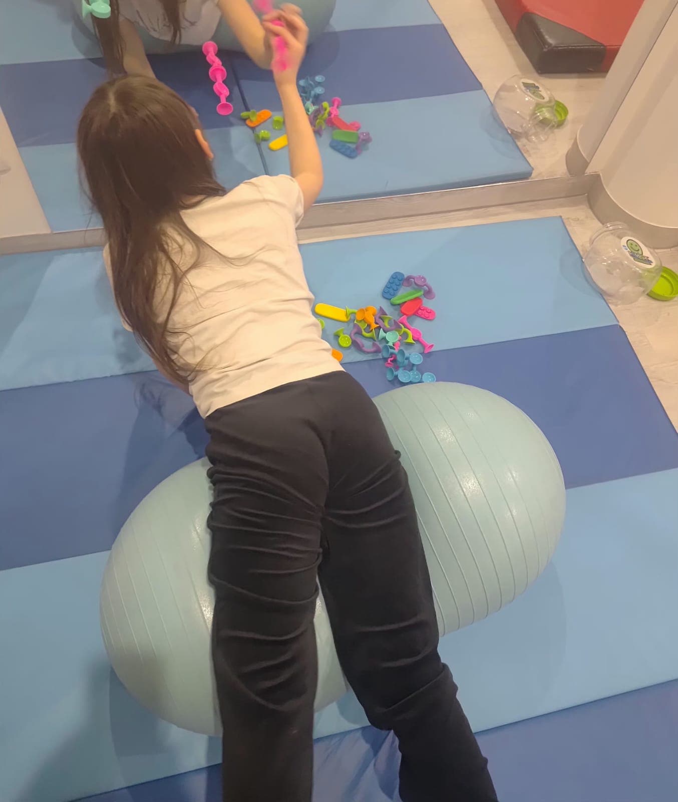 Dziecko wykonuje ćwiczenie ruchowe na materacu podczas terapii.
