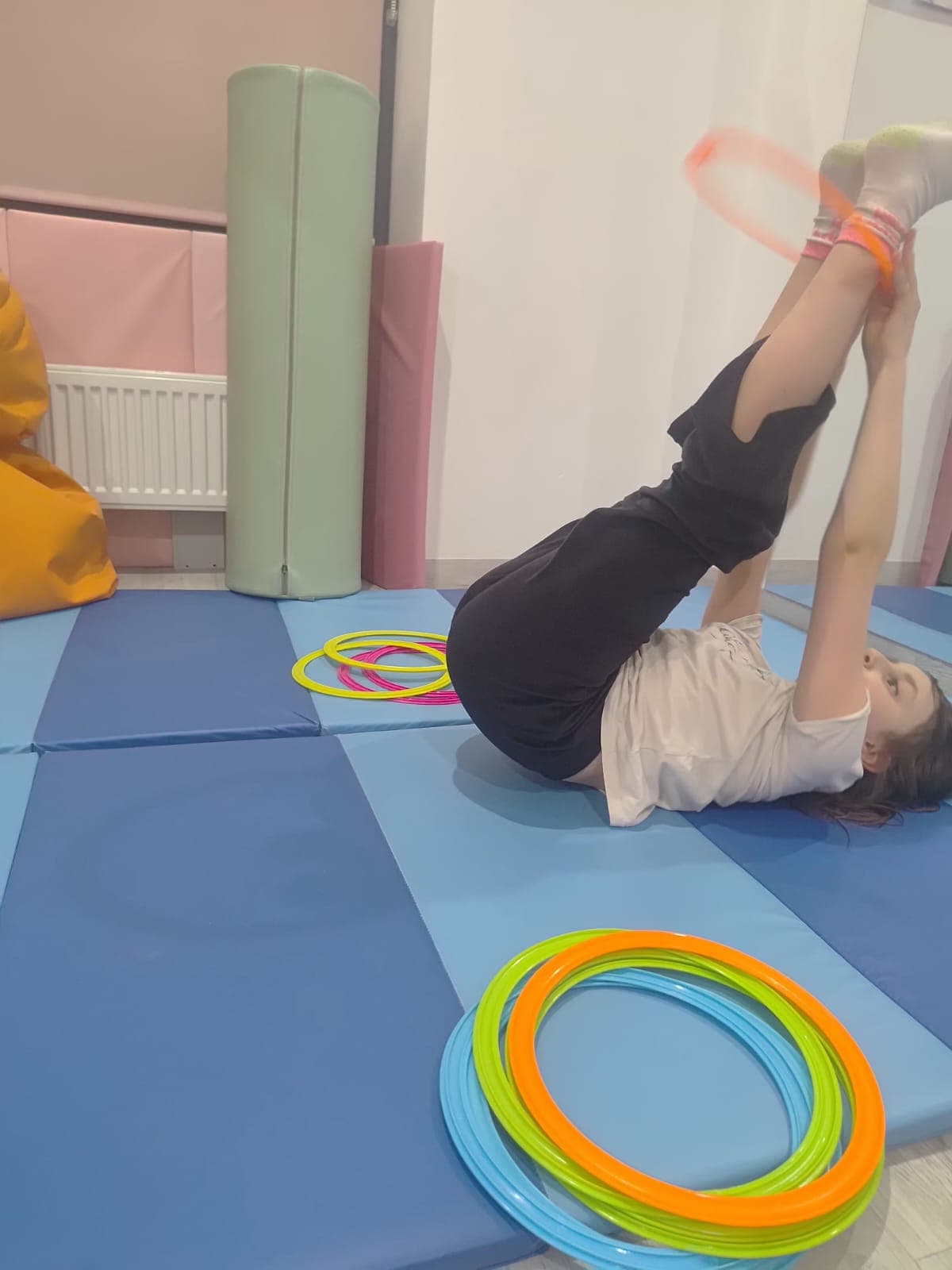 Dziecko wykonuje ćwiczenie ruchowe na materacu podczas terapii.