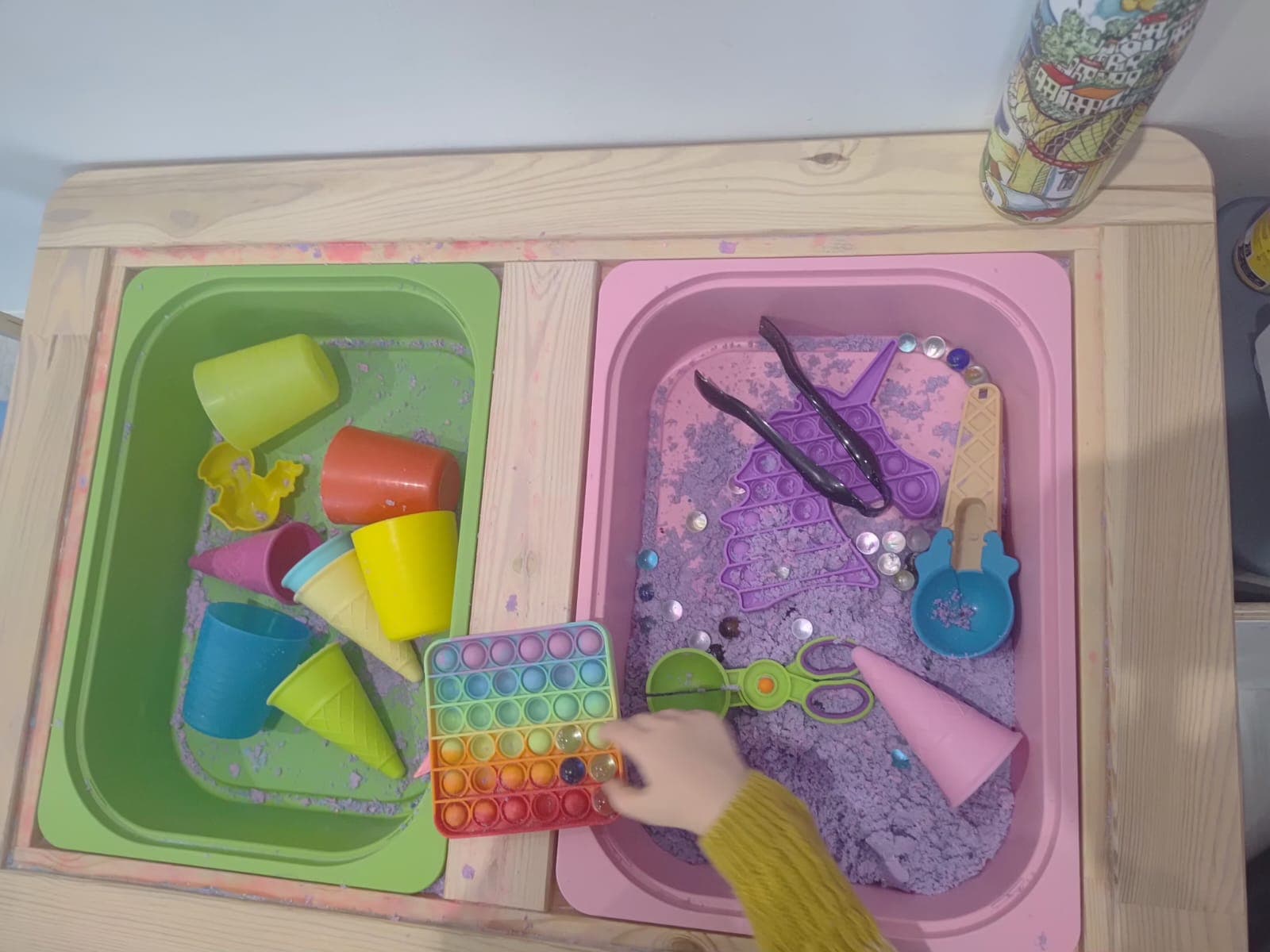 Dziecko wykonuje sensoryczne zadanie manualne przy stoliku.